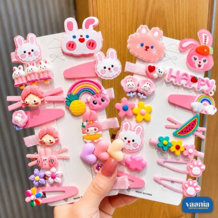 A hand holding three cards of pink Sweet Charm Hair Clips featuring rabbits, rainbows, and flowers.