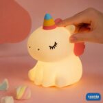 A glowing Sitting Unicorn Silicone Night Lamp with a colorful horn and pink wings on a pink background. - view 3