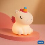A glowing Sitting Unicorn Silicone Night Lamp with a colorful horn and pink wings on a pink background. - view 5