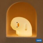 A glowing Why Duck Silicone Night Lamp resting inside a warm arched wall niche.