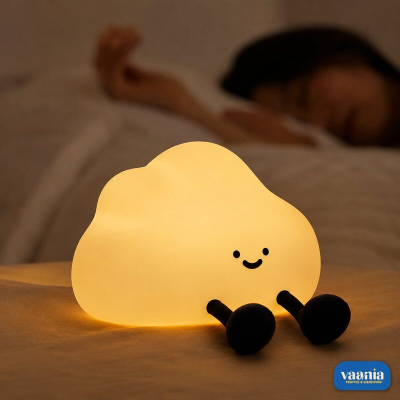 A glowing warm yellow One Cloud Silicone Night Lamp with a smiling face nestled in soft white cotton stuffing. - view 2