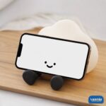 A glowing warm yellow One Cloud Silicone Night Lamp with a smiling face nestled in soft white cotton stuffing. - view 4
