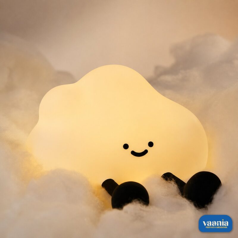 A glowing warm yellow One Cloud Silicone Night Lamp with a smiling face nestled in soft white cotton stuffing.