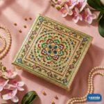 Top view of a square gold Metal Leg Chowki with colorful floral mandala patterns on a pink fabric background.