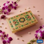 A stack of four golden nested Rectangular Chowkis with floral paintings surrounded by pink orchids and pearls. - view 3