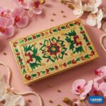 A stack of four golden nested Rectangular Chowkis with floral paintings surrounded by pink orchids and pearls. - view 5