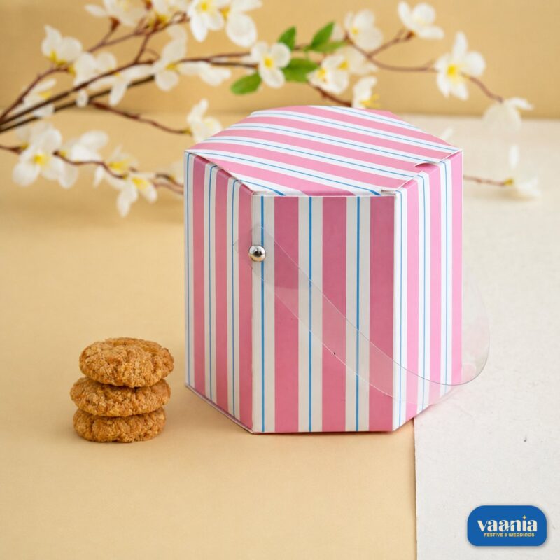 A pink and white striped hexagonal Multi Purpose Box with a clear handle next to a stack of cookies.