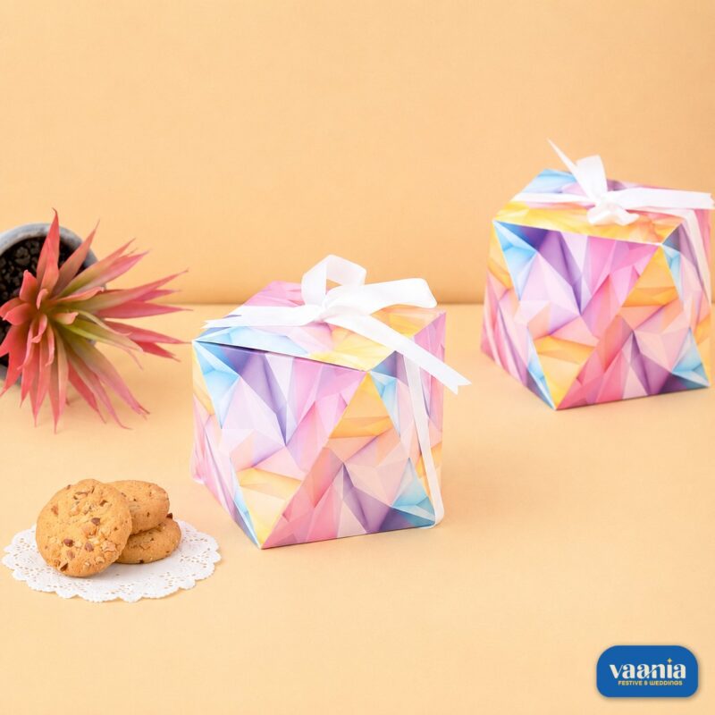Two Diamond Box gift containers with geometric patterns and white ribbons next to cookies and a succulent plant.