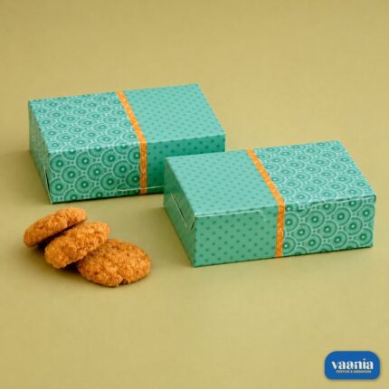 Two teal patterned Multi Purpose Boxes sitting next to three golden brown cookies on a neutral background.