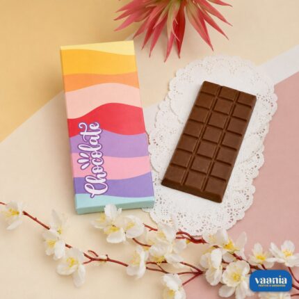 A milk chocolate bar next to a colorful wavy patterned Chocolate Bar Box with floral accents.