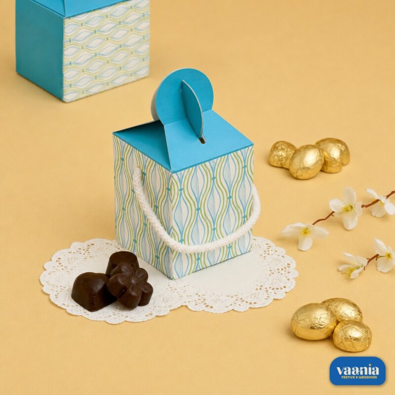 A blue and white patterned Multi Purpose Box with a rope handle sits next to chocolates and golden eggs.