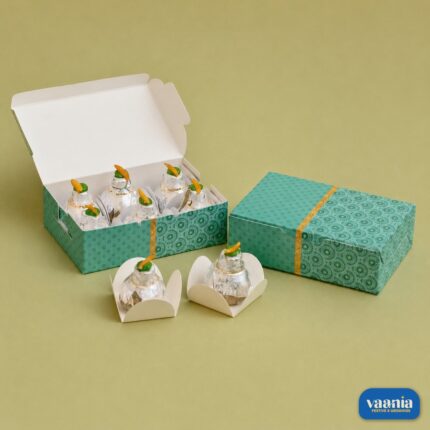 A teal patterned 6 Cavity Box featuring small silver decorative items in separate white liners.