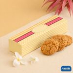 A decorative yellow patterned Multi Purpose Box beside three golden brown cookies and white flowers.