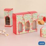 A floral Hamper Bag Set with three arched windows and three matching inner boxes filled with cookies on a pink surface.