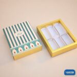 A teal striped sliding box with floral accents next to its gold six-cavity insert for Sliding Box - Cavity Box.