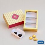 A decorative Sliding Box - Cavity Box (3 Big Cavity) with a striped lid, gold tray, and loose chocolates.