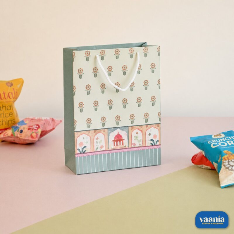 A decorative Gift Carry Bag with floral patterns and heritage arch illustrations sitting next to snack packets.