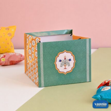 Green and orange floral patterned Gift Carry Bag with elegant handles on a dual-tone surface.
