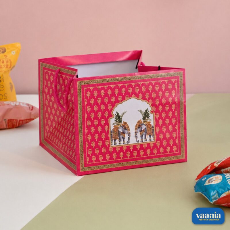 A pink square Gift Carry Bag with elephant illustrations and gold patterns on a white and green surface.