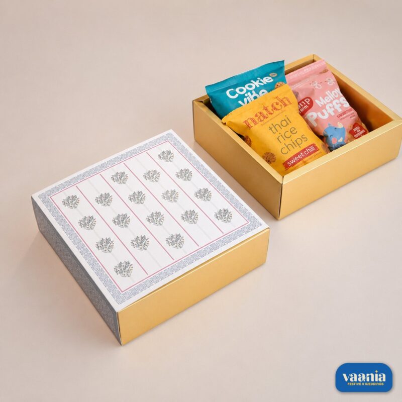 A luxury gold Sliding Box with Tray featuring a floral lid and filled with snacks alongside a closed matching box.