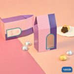 Two pink and purple Window Candy Boxes styled with gold and silver wrapped chocolates on a dual-tone background.