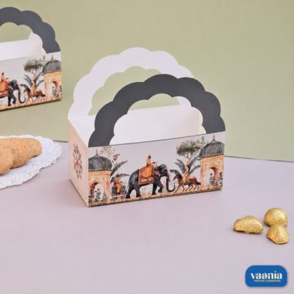 A decorative Hamper Bucket with royal Indian prints and scalloped handles sitting next to cookies and chocolates.