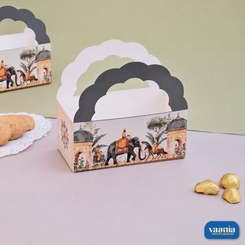 A decorative Hamper Bucket with royal Indian prints and scalloped handles sitting next to cookies and chocolates.