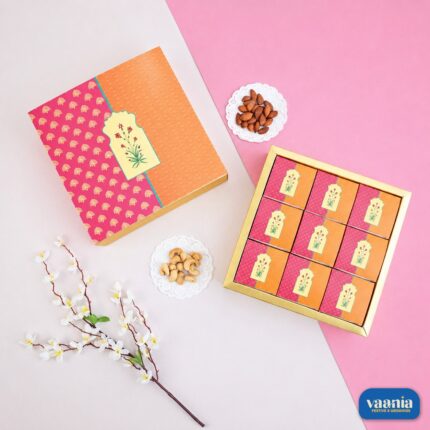 Top view of an orange and pink floral Sliding Box with nine smaller inner boxes beside decorative almonds and cashews.