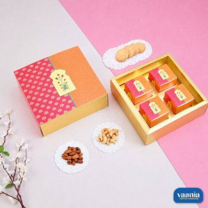 An ornate orange and pink Sliding Box with four inner containers next to almonds, cashews, and cookies.