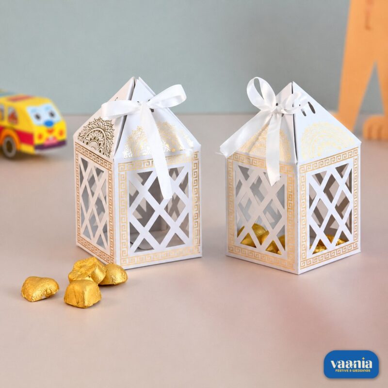 Two white and gold Hut Chocolate Boxes with lattice cutouts and satin ribbons filled with gold-wrapped chocolates.