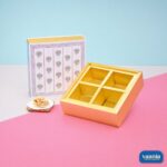 A floral patterned sliding box with a 4-compartment gold tray and a small pile of cashews.