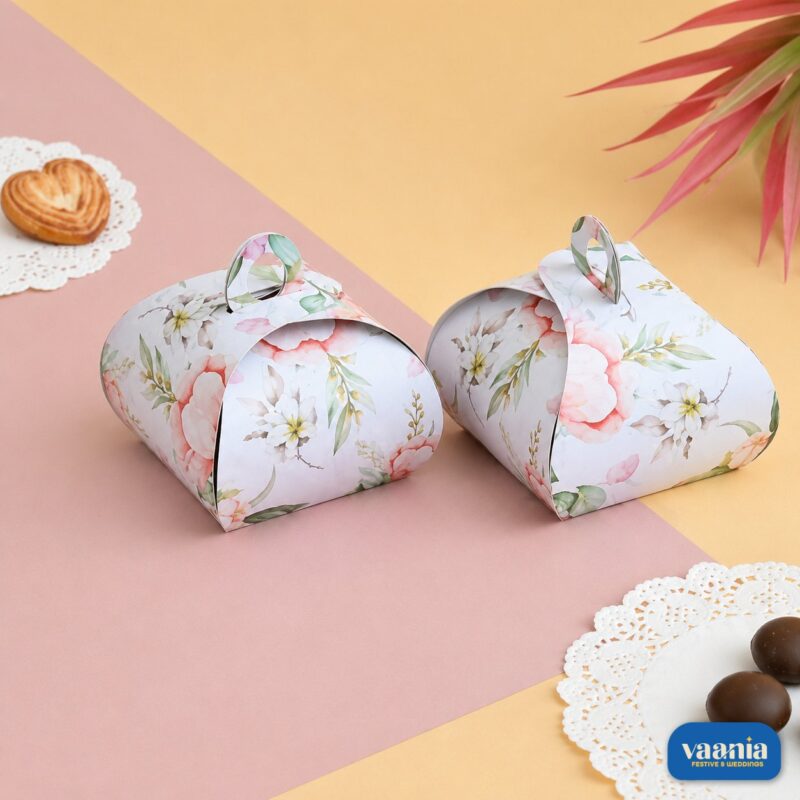 Two white Multi Purpose Boxes featuring pink floral patterns with circular handles resting on a pink and yellow background.