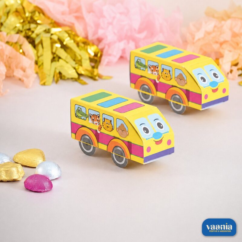 Two yellow Paper Bus Jungle Bus favor boxes with animal illustrations and colorful chocolates on a decorated tabletop.