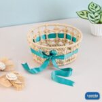 A handcrafted Round Hamper Basket made of tan jute with an interwoven teal satin ribbon and bow.