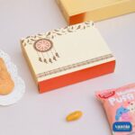 Cream and orange Sliding Box with dreamcatcher illustration next to cookies and a snack pack.