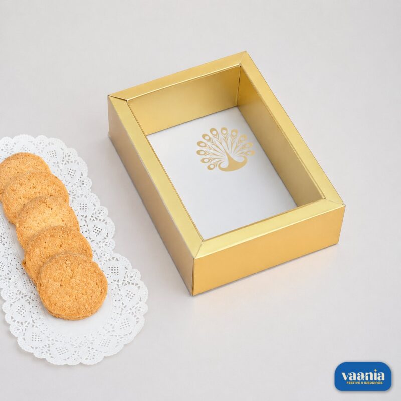 A golden Sliding PVC Box with a peacock logo sitting next to cookies on a white doily.