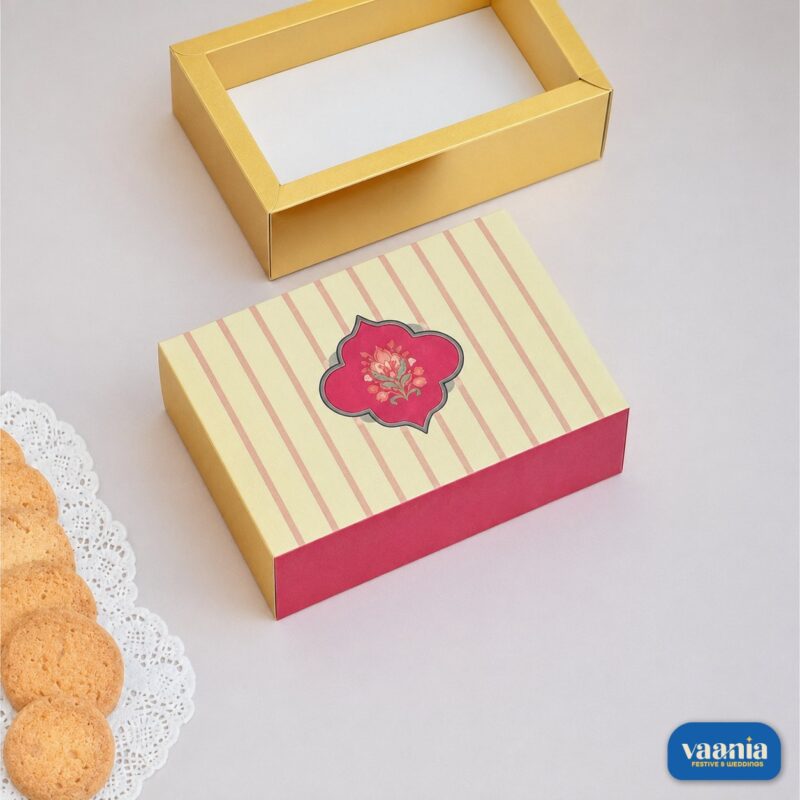 A decorative beige and pink striped Sliding Box next to an open gold tray and fresh cookies.