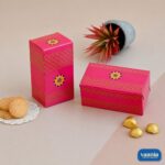 Two pink Vaania Multi Purpose Boxes with gold patterns shown with cookies and chocolates on a neutral background.